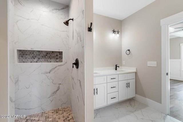 bathroom with marble finish floor, baseboards, vanity, and a marble finish shower