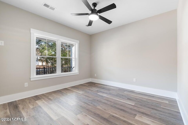 spare room with visible vents, ceiling fan, baseboards, and wood finished floors