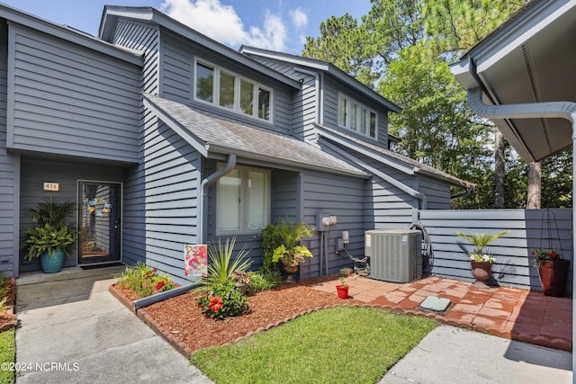 exterior space with central air condition unit, a shingled roof, and fence