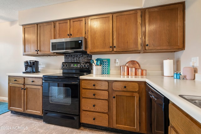 kitchen with black appliances, a textured ceiling, and light tile patterned floors