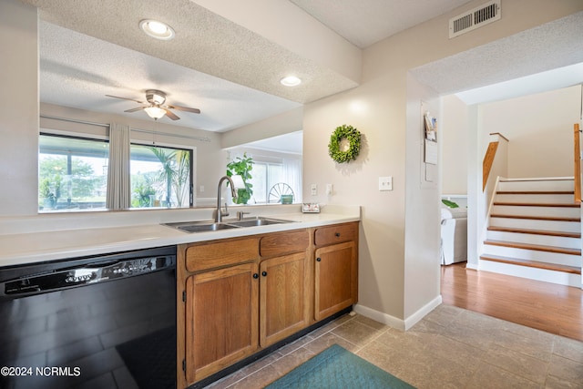 kitchen with black dishwasher, light hardwood / wood-style flooring, sink, a textured ceiling, and ceiling fan