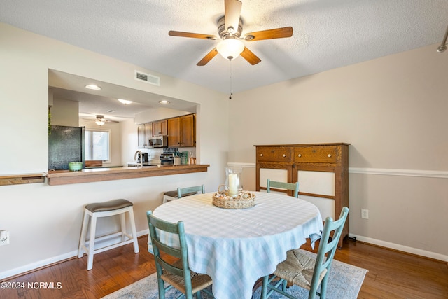 dining area featuring ceiling fan, a textured ceiling, sink, and hardwood / wood-style floors