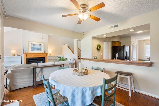 dining space featuring a textured ceiling, wood-type flooring, and ceiling fan