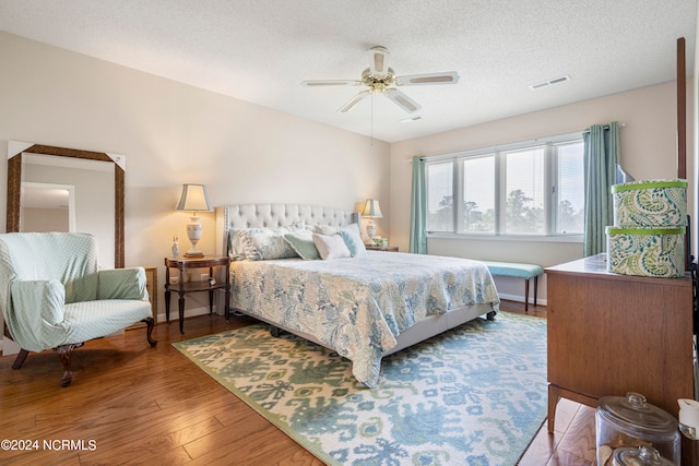 bedroom with ceiling fan, wood-type flooring, and a textured ceiling