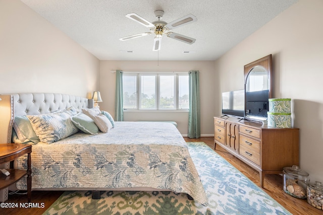 bedroom featuring a textured ceiling, multiple windows, hardwood / wood-style flooring, and ceiling fan