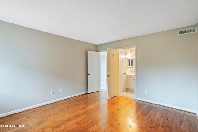 interior space with light hardwood / wood-style floors, a textured ceiling, and ensuite bathroom