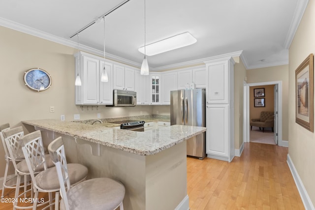 kitchen with appliances with stainless steel finishes, decorative light fixtures, white cabinetry, a breakfast bar area, and kitchen peninsula