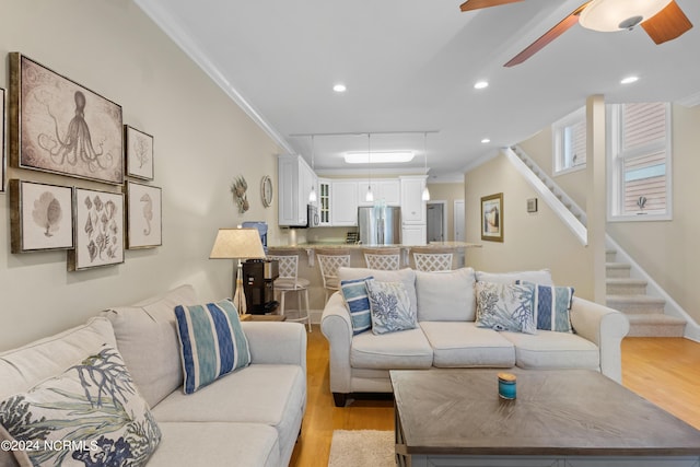 living room with ornamental molding, ceiling fan, and light hardwood / wood-style floors