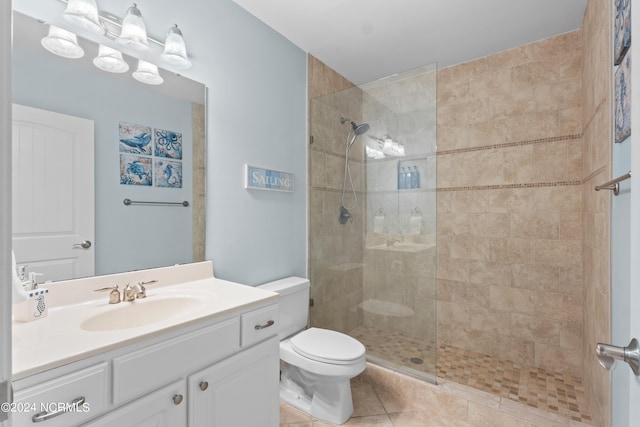 bathroom with tiled shower, vanity, toilet, and tile patterned floors