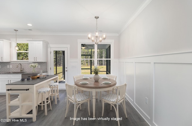 dining room featuring an inviting chandelier, sink, dark wood-type flooring, and ornamental molding