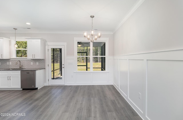 unfurnished dining area featuring ornamental molding, sink, a notable chandelier, and light hardwood / wood-style floors