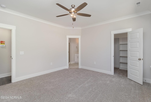 unfurnished bedroom featuring ceiling fan, ornamental molding, light carpet, a spacious closet, and a closet