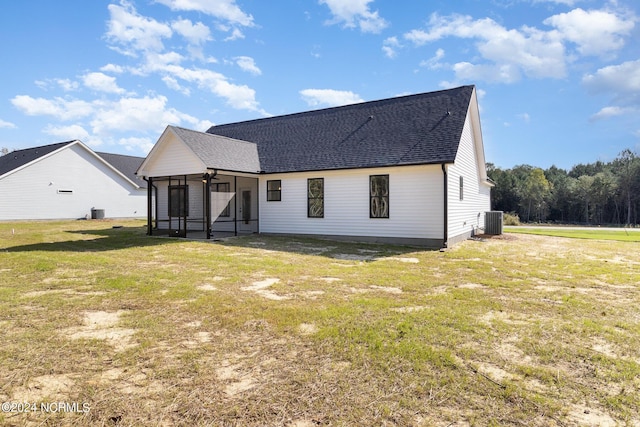 rear view of house with a sunroom, central AC unit, and a lawn