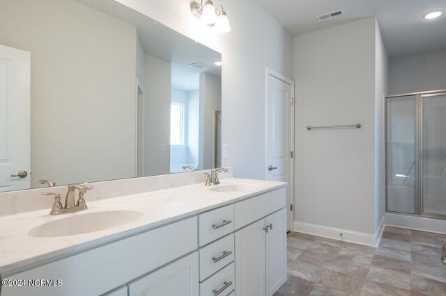 bathroom featuring double vanity, a stall shower, a sink, and visible vents