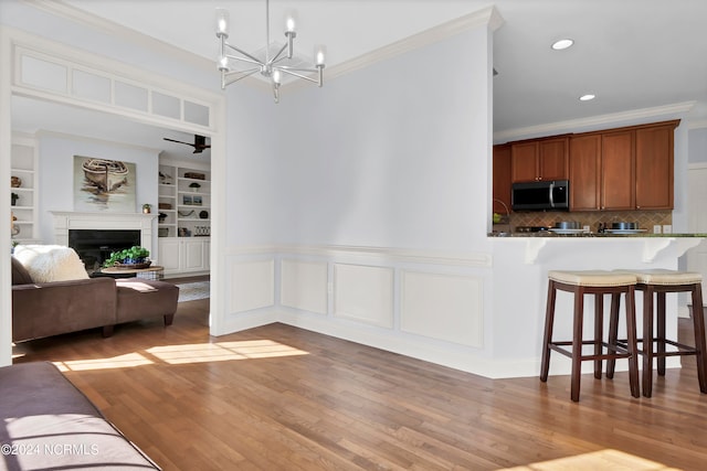 dining room featuring ornamental molding, a notable chandelier, built in shelves, and wood-type flooring