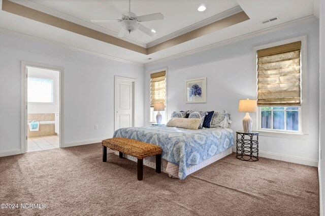 carpeted bedroom with ceiling fan, a tray ceiling, crown molding, and ensuite bathroom