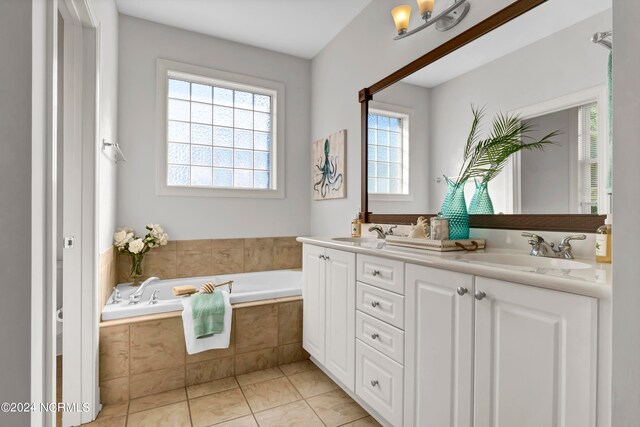 bathroom featuring tiled tub, vanity, and tile patterned floors