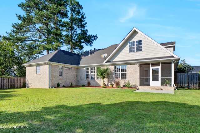 rear view of house featuring a yard and a sunroom