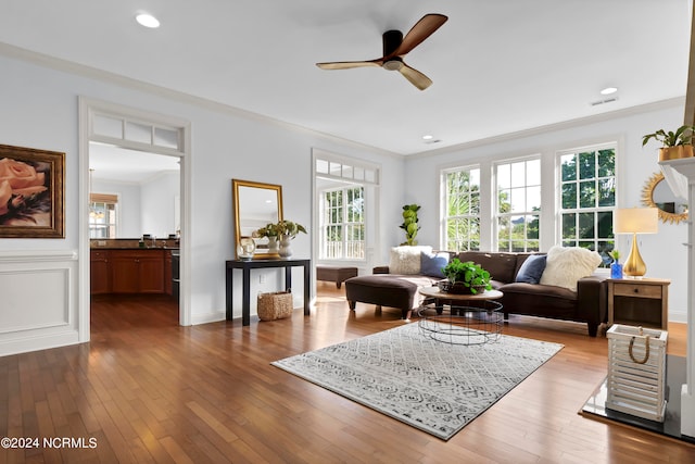 living room with wood-type flooring, ornamental molding, and ceiling fan