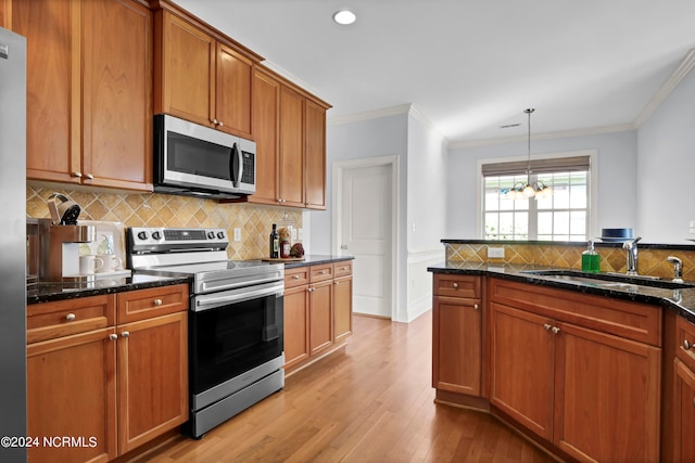 kitchen featuring stainless steel appliances, sink, light hardwood / wood-style floors, crown molding, and hanging light fixtures