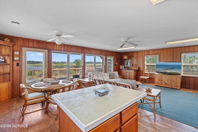 kitchen with a kitchen island, ceiling fan, tile counters, and light carpet