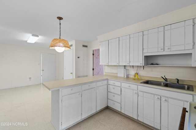 kitchen with decorative light fixtures, sink, white cabinets, light tile patterned floors, and kitchen peninsula