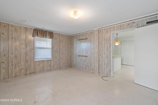 tiled spare room featuring wood walls and a textured ceiling