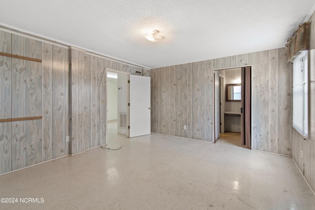 empty room with a textured ceiling and wooden walls