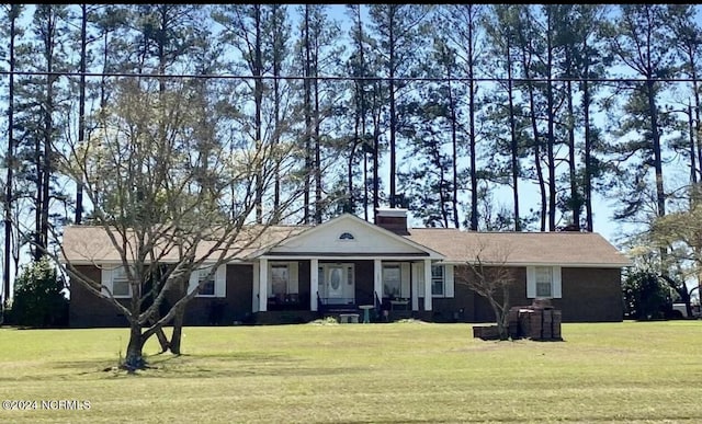 view of front of house featuring a front yard, covered porch, and a chimney