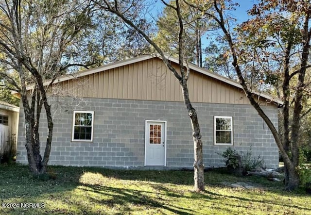 rear view of property featuring concrete block siding and a lawn