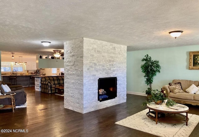 living room featuring a textured ceiling, ceiling fan, a stone fireplace, wood finished floors, and visible vents