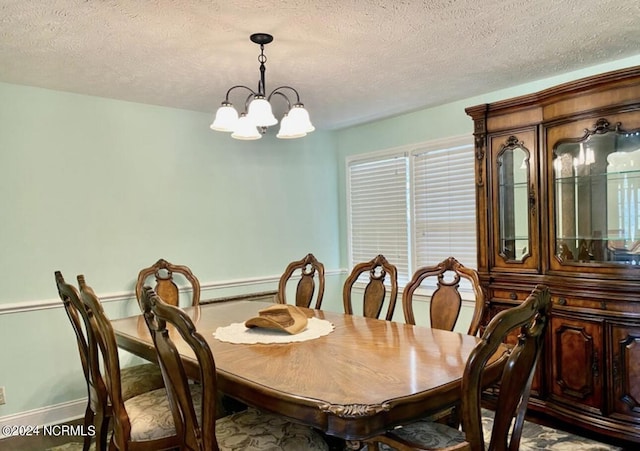 dining area with a textured ceiling, baseboards, and a notable chandelier