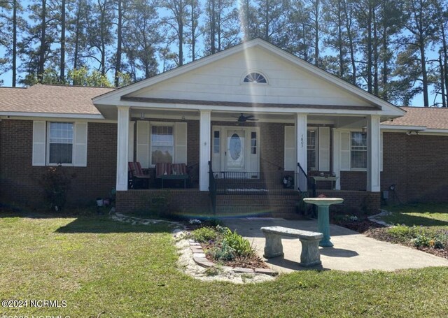 view of front of house with ceiling fan, covered porch, and a front yard