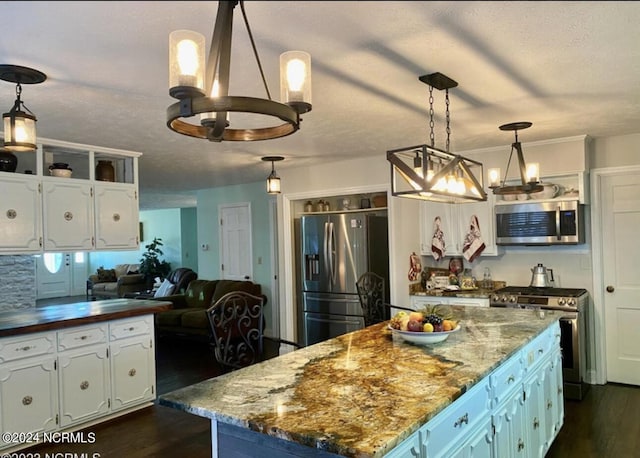 kitchen with an inviting chandelier, white cabinetry, appliances with stainless steel finishes, and dark wood-style flooring