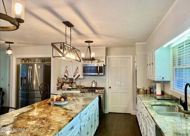 kitchen featuring dark wood-style floors, stainless steel appliances, hanging light fixtures, a sink, and light stone countertops