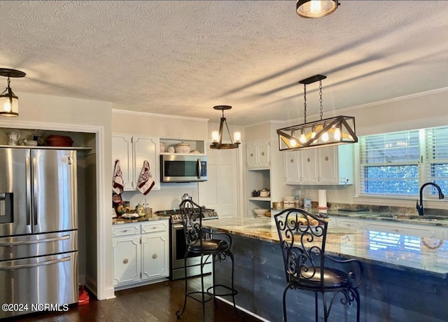 kitchen featuring stainless steel appliances, white cabinets, a sink, and a kitchen bar