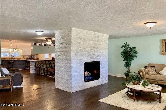 living room with a textured ceiling, a fireplace, wood finished floors, and a ceiling fan