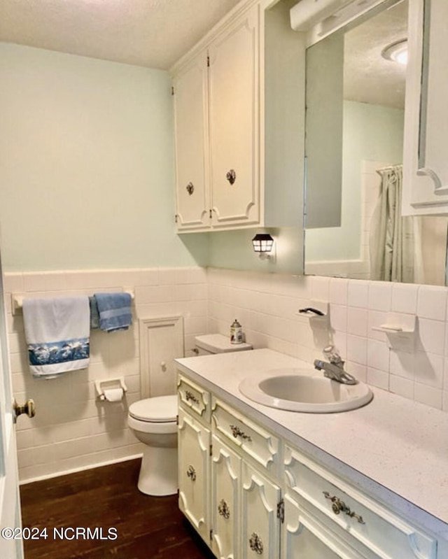 bathroom featuring wood finished floors, toilet, vanity, wainscoting, and a shower with shower curtain