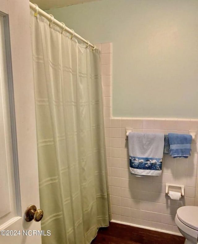 bathroom featuring tile walls, toilet, wood finished floors, wainscoting, and a shower with curtain