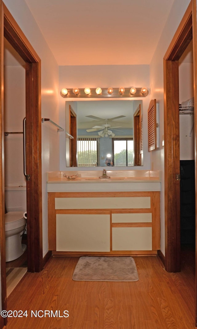 bathroom featuring toilet, ceiling fan, wood finished floors, and vanity