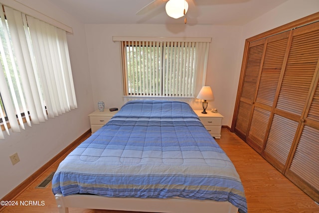 bedroom featuring wood finished floors, a ceiling fan, visible vents, baseboards, and a closet