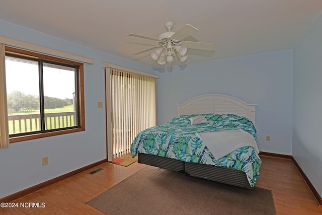 bedroom with a ceiling fan, baseboards, visible vents, and wood finished floors