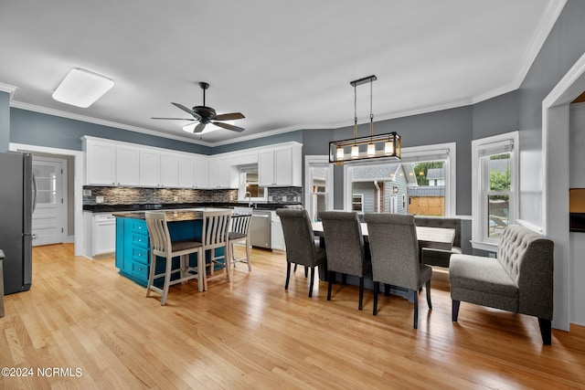 dining space featuring ceiling fan, crown molding, and light wood-type flooring