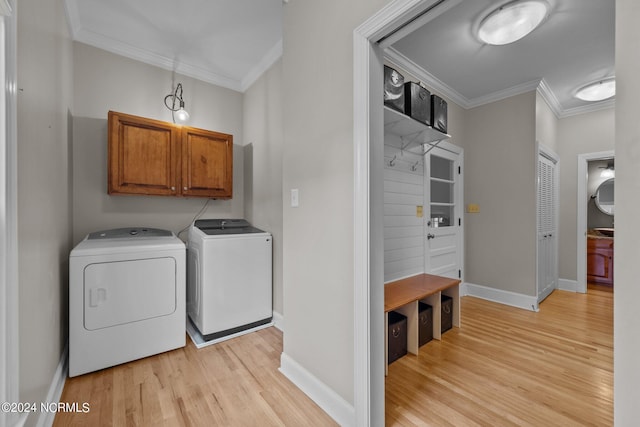 laundry area with washer and clothes dryer, cabinet space, ornamental molding, light wood-type flooring, and baseboards