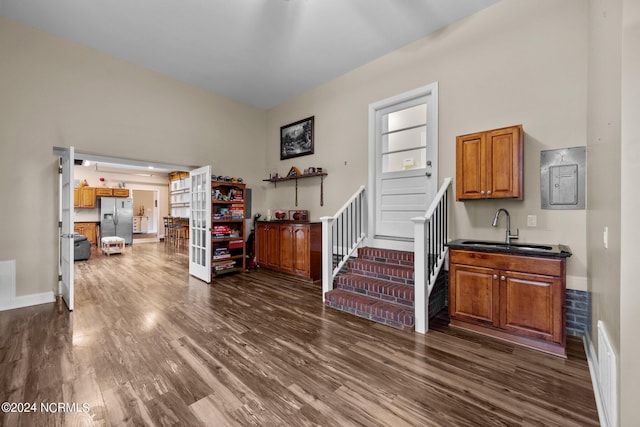 interior space featuring sink, a towering ceiling, and dark wood-type flooring