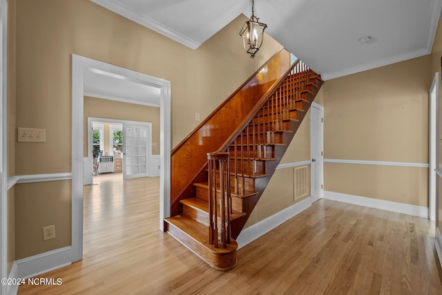 stairway with french doors, hardwood / wood-style flooring, and crown molding