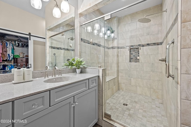 bathroom featuring a spacious closet, a stall shower, and vanity