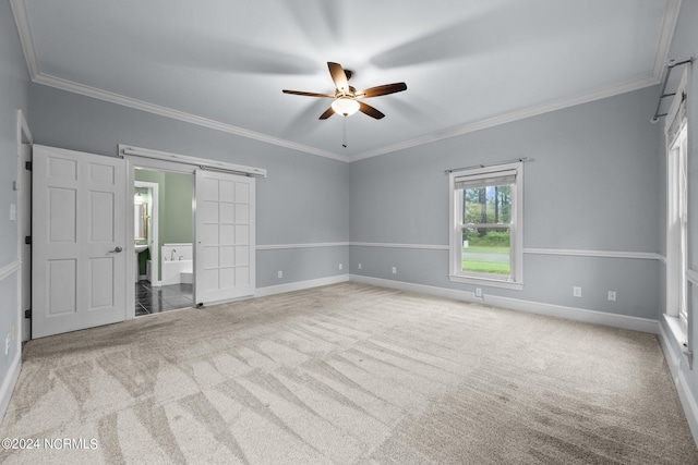 unfurnished room featuring a barn door, ornamental molding, ceiling fan, and light colored carpet
