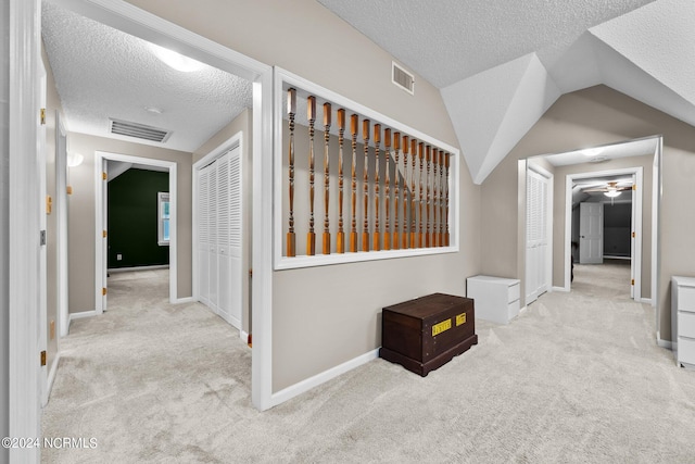 hallway featuring a textured ceiling, vaulted ceiling, and carpet