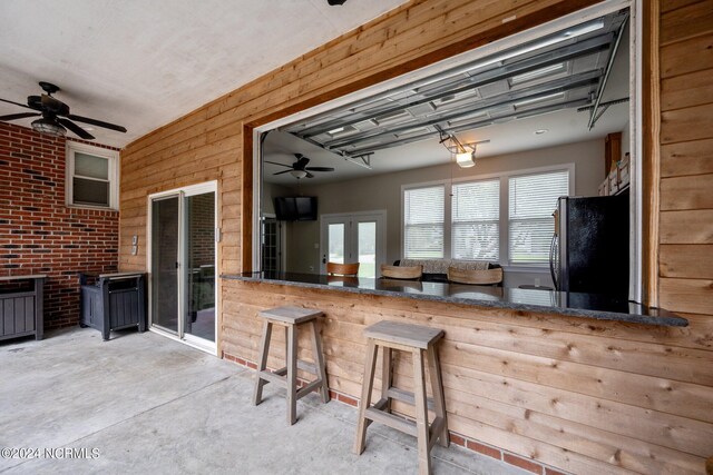 kitchen featuring ceiling fan, fridge, concrete flooring, and brick wall